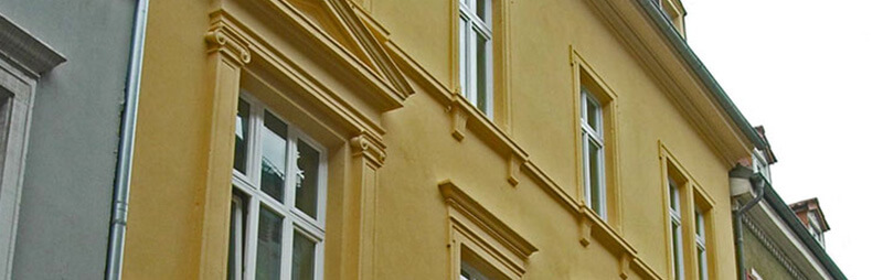 Gelbes Altbau-Wohnheim mit klassizistischen Fassadenelementen und weißen Fenstern in stilvoller Altstadtlage