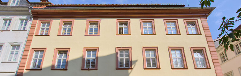 Historisches Gebäude mit hellgelber Fassade, roten Fensterrahmen und markantem Giebel in der Altstadt