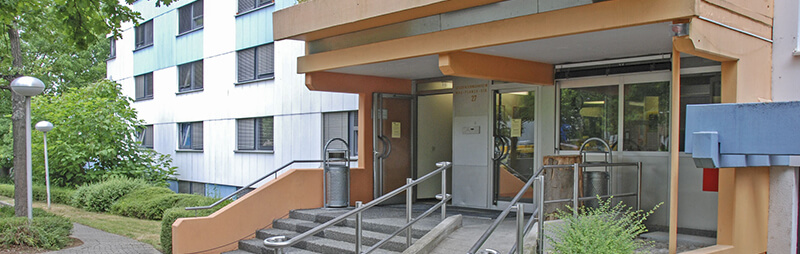 Barrierefreier Eingangsbereich eines Wohnheims mit Rampe, Treppen und orangefarbenem Vordach