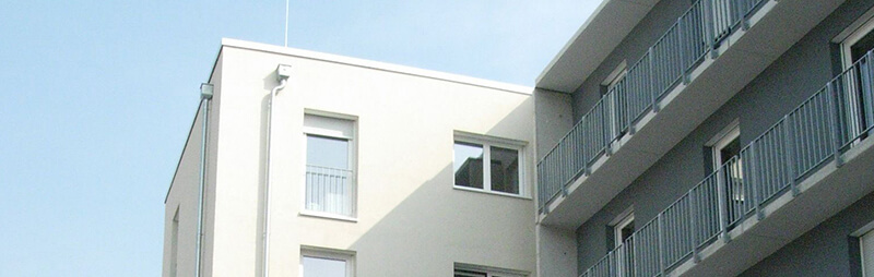 Schlichtes Wohnheim mit heller Fassade und umlaufenden Balkonen, nüchtern-moderne Architektur