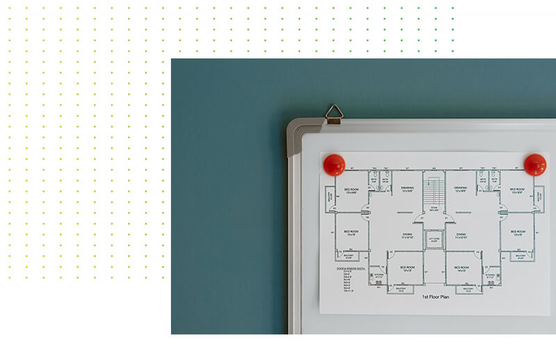 Ein Grundriss ist mit roten Magneten an einem Whiteboard an einer blaugrünen Wand befestigt. Auf der linken Seite befindet sich ein Muster aus kleinen gelbgrünen Punkten auf weißem Hintergrund.