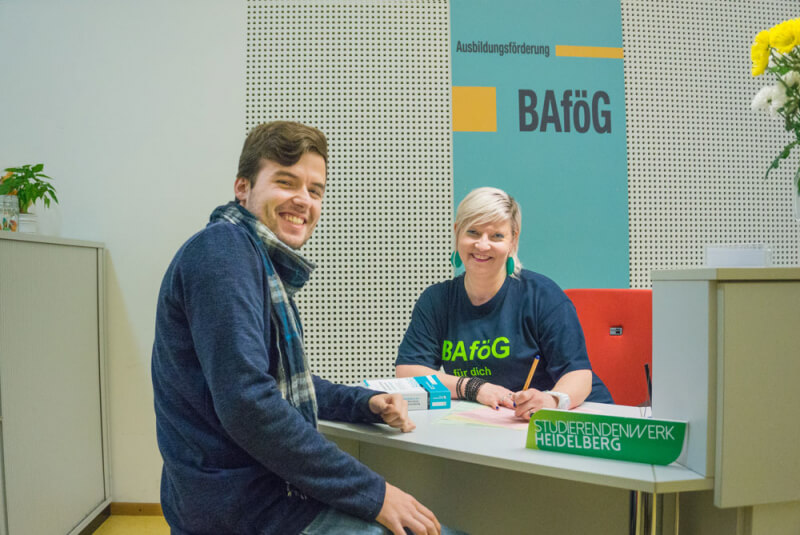 Lächelnder Student im Beratungsgespräch mit einer BAföG-Mitarbeiterin im Studierendenwerk Heidelberg