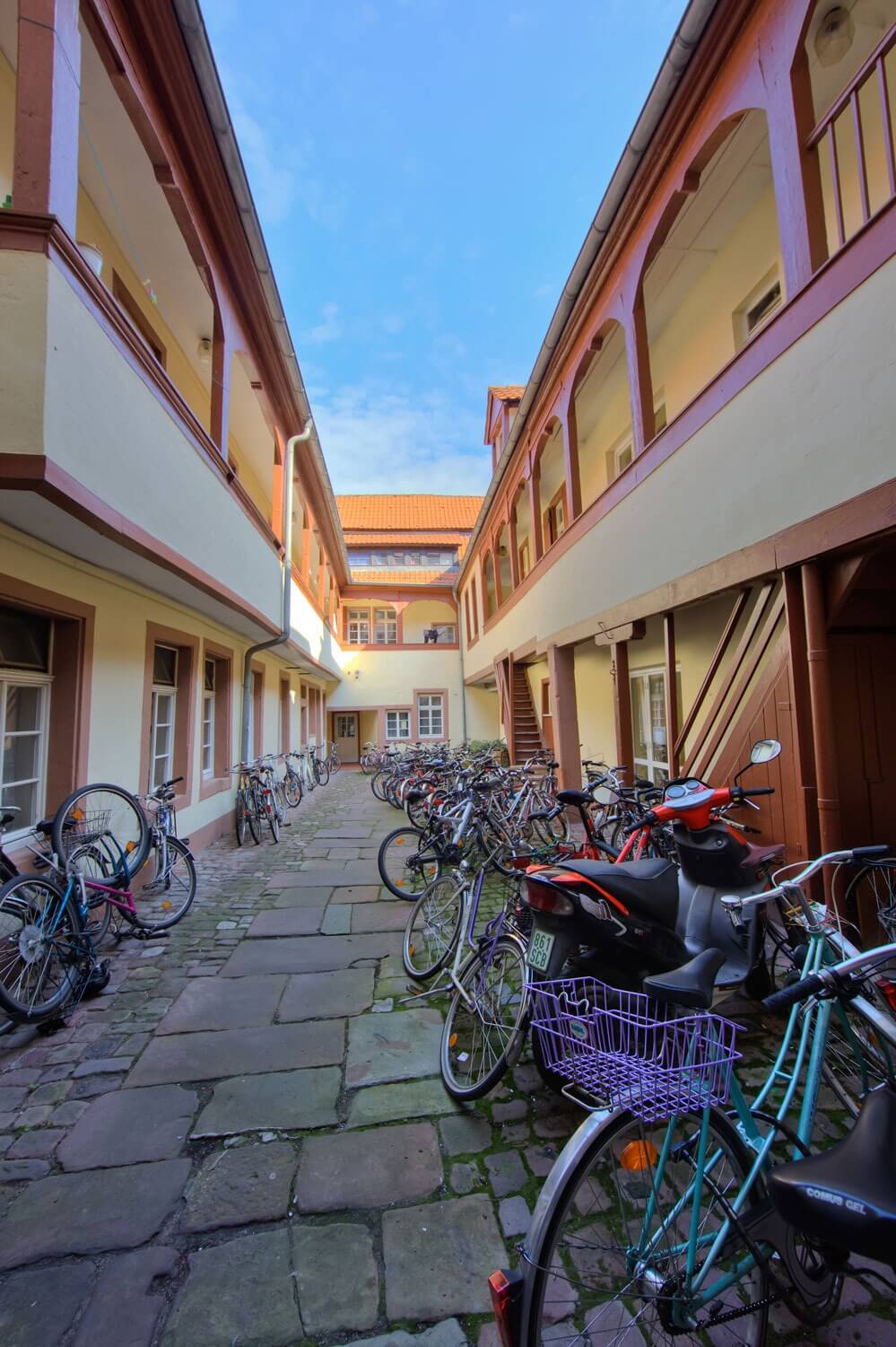 Innenhof mit zahlreichen abgestellten Fahrrädern zwischen zwei Gebäudeflügeln mit offenen Laubengängen.