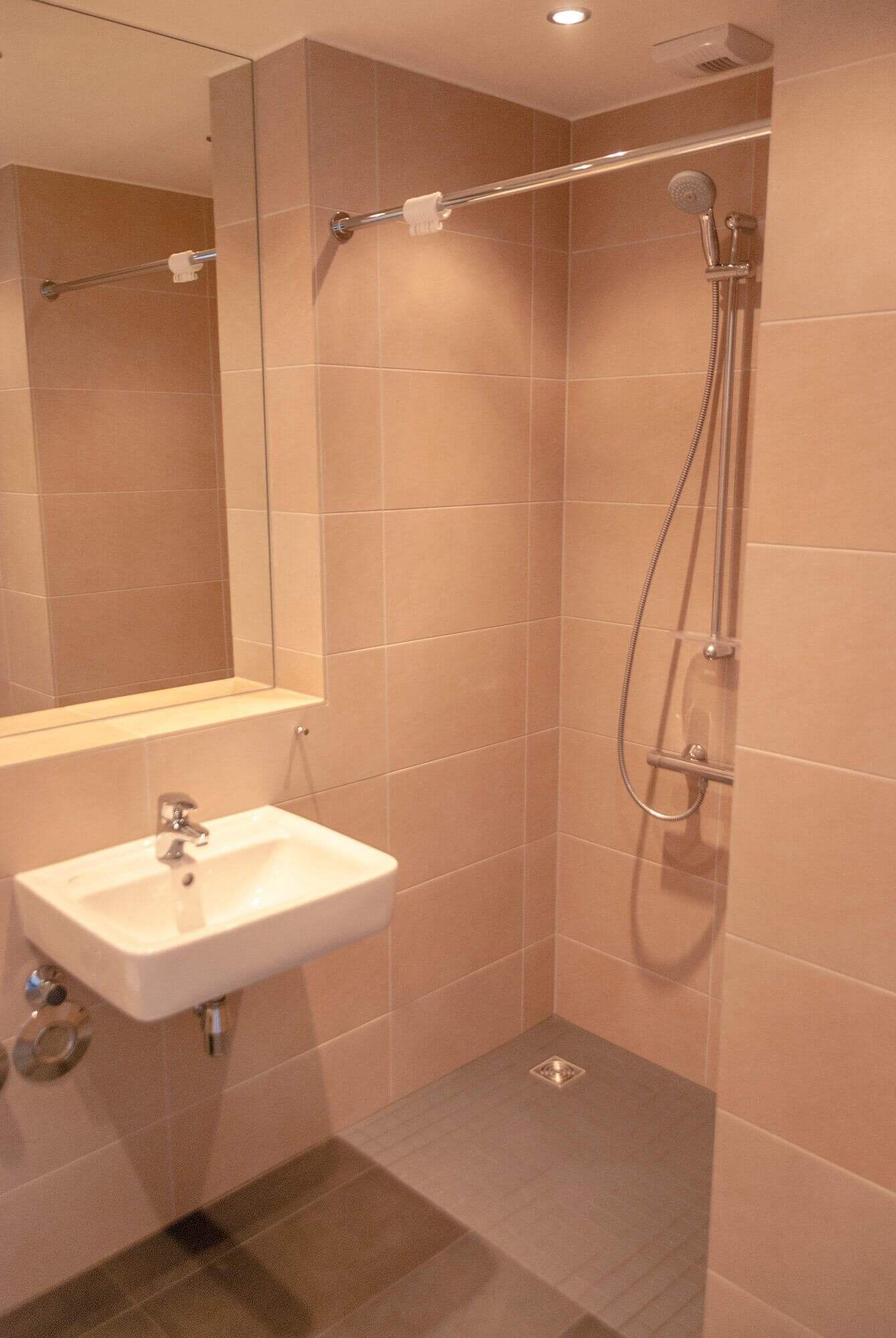 Modern tiled bathroom in the student residence with washbasin, mirror and walk-in shower