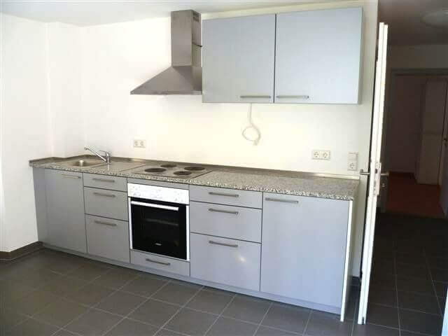 Ein kombinierter Wohn- und Essbereich mit Küche, Esstisch, vier Stühlen, gemütlicher Sitzecke und Fernseher in einer funktional eingerichteten Wohnung.